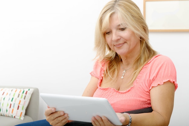 Hermosa mujer madura con tableta en casa