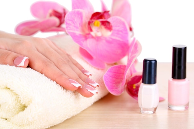 Hermosa mujer manos con manicura francesa y flores en la mesa sobre fondo blanco.