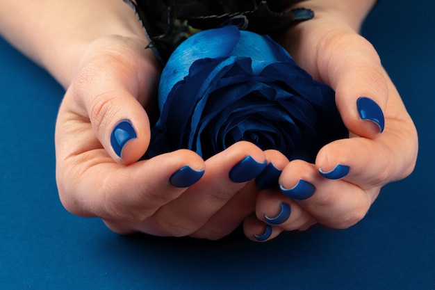 Hermosa mujer manos con manicura con rosas en color azul clásico