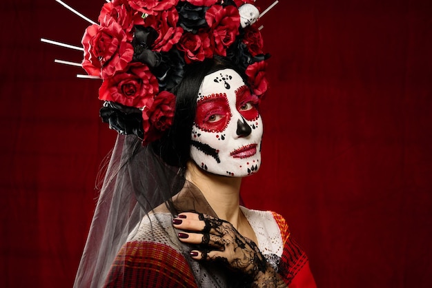 Hermosa mujer con un maquillaje de calavera de azúcar con una corona de flores en la cabeza, fondo rojo.