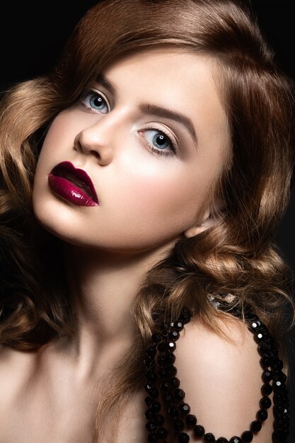 Foto hermosa mujer con maquillaje de noche, labios rojos y rizos.