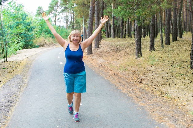 Hermosa mujer mayor corriendo al aire libre en el parque.