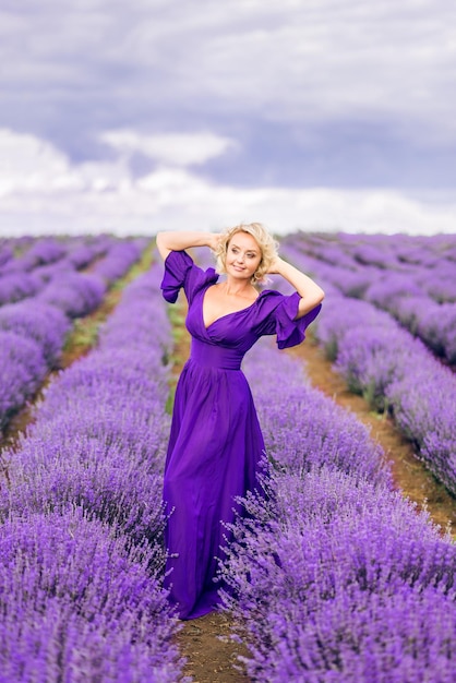 Hermosa mujer mayor con un largo vestido morado Una anciana en un campo de lavanda