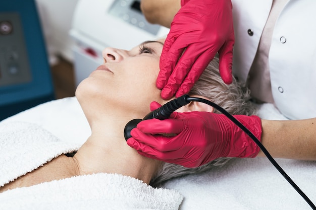 Hermosa mujer mayor con mesoterapia en el salón de belleza cosmética.