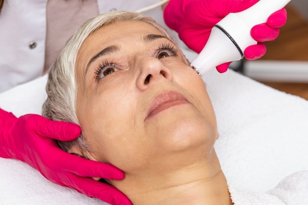 Hermosa mujer mayor con ondas de radio levantando tratamiento facial.