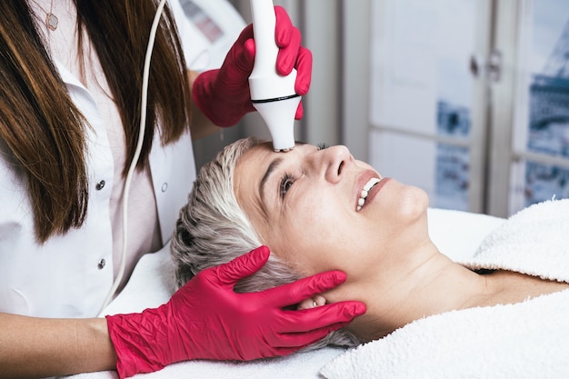 Hermosa mujer mayor con ondas de radio levantando tratamiento facial.