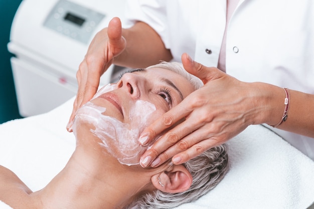 Hermosa mujer mayor recibiendo tratamiento de masaje spa en el salón de belleza spa. Tratamiento de belleza facial.