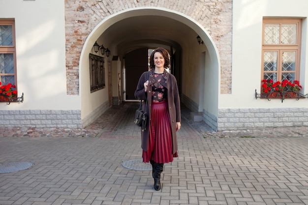 Hermosa mujer de mediana edad caminando por la calle en un soleado día de otoño o primavera.