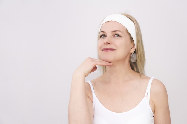 Foto hermosa mujer de mediana edad hace automasaje de la cara, ejercicio para deshacerse de la papada