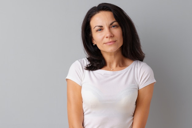 Hermosa mujer de mediana edad posando sobre un fondo gris