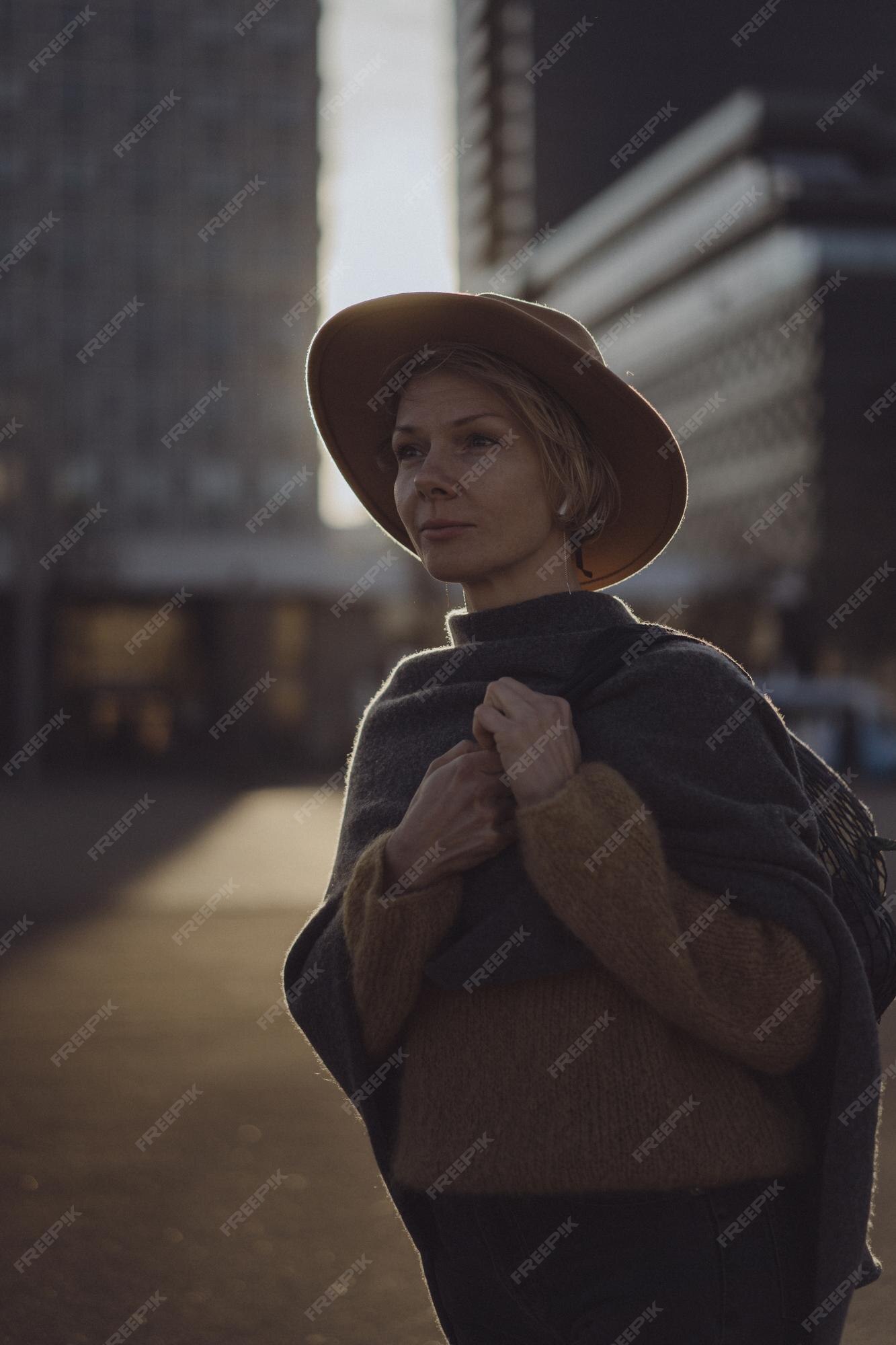 Hermosa mujer de mediana edad con un sombrero con un corte de pelo corto en el centro de una gran ciudad. retrato de primer plano, de fondo | Foto Premium