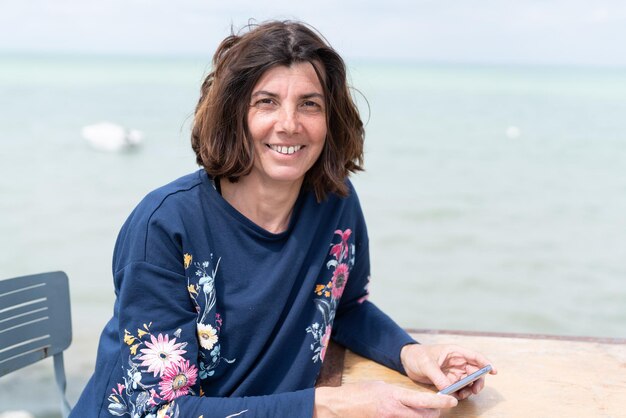 Hermosa mujer de mediana edad sonriendo riendo en la playa disfrutando del verano en la costa de la mesa