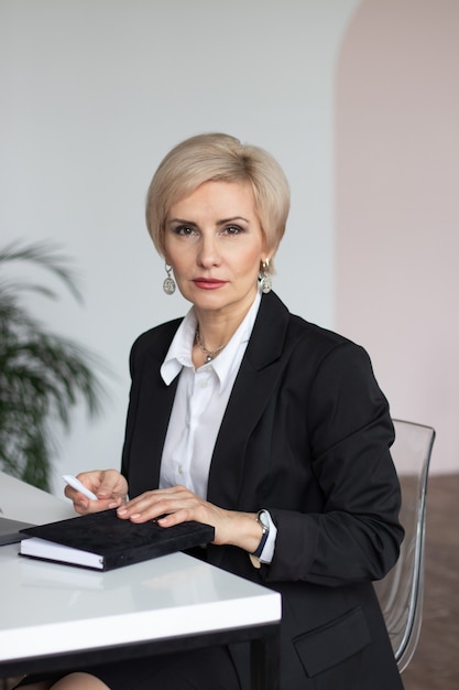 Hermosa mujer de mediana edad vestida con ropa de negocios en la mesa