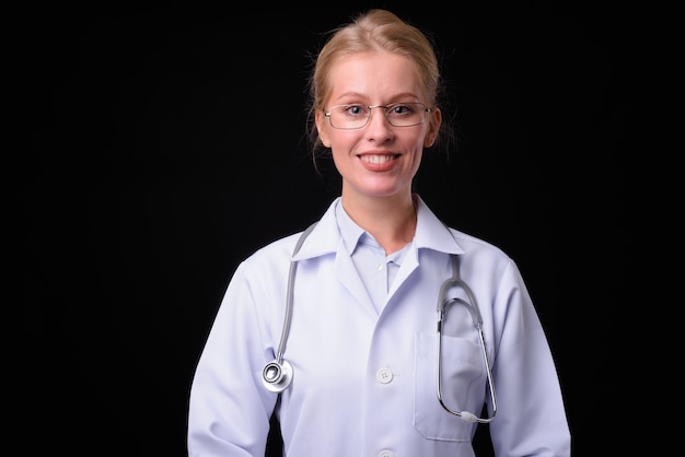 Hermosa mujer médico con cabello rubio contra la pared negra