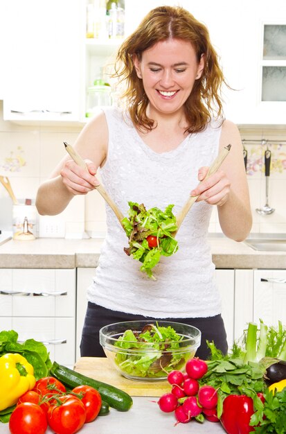 Foto hermosa mujer mezclando una ensalada en su cocina