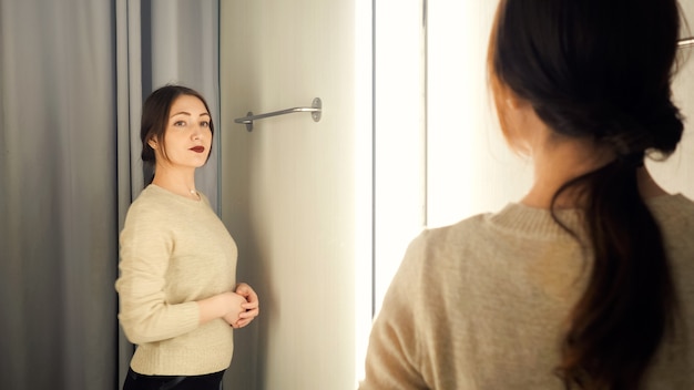 Hermosa mujer mide la ropa en un probador.