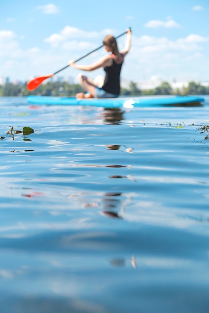 Hermosa mujer milenaria en una tabla de SUP en el río