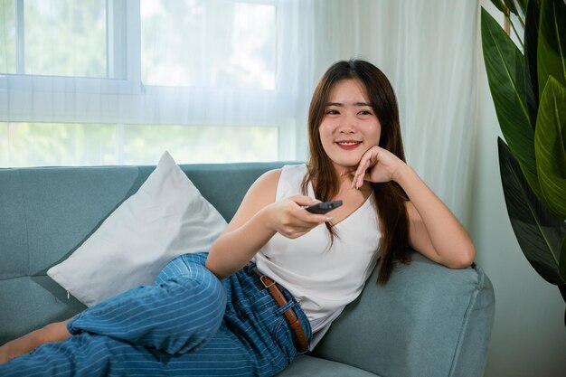 Hermosa mujer mira una película sosteniendo un control remoto viendo televisión