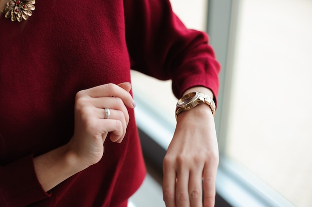 Hermosa mujer mira el reloj junto a la ventana