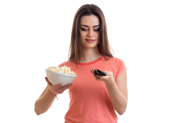 Hermosa mujer mira la televisión con palomitas de maíz aislado sobre fondo blanco.