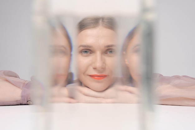 Hermosa mujer mirando a través del agua de cristal mira a la cámara naranja brillante