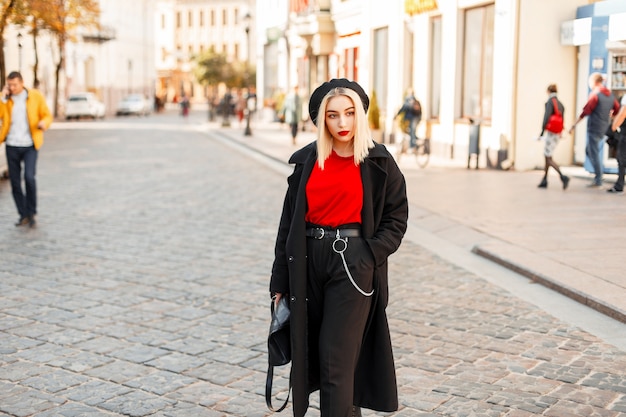 Hermosa mujer de moda en elegante ropa de otoño negro posando en la ciudad en un día de otoño