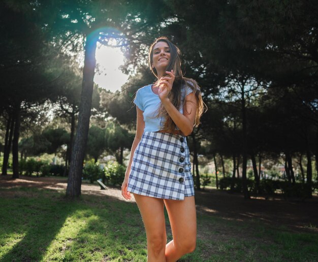 Hermosa mujer de moda joven en ropa sexy posando en el parque verde. Foto de concepto de verano