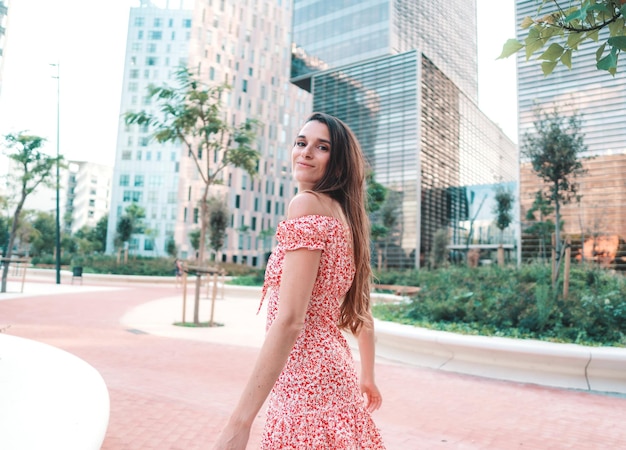 Hermosa mujer de moda joven en sexy vestido elegante posando en la ciudad moderna con rascacielos en el fondo