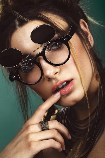 Hermosa mujer de moda con peinado de maquillaje creativo con gafas y cara de belleza de joyería