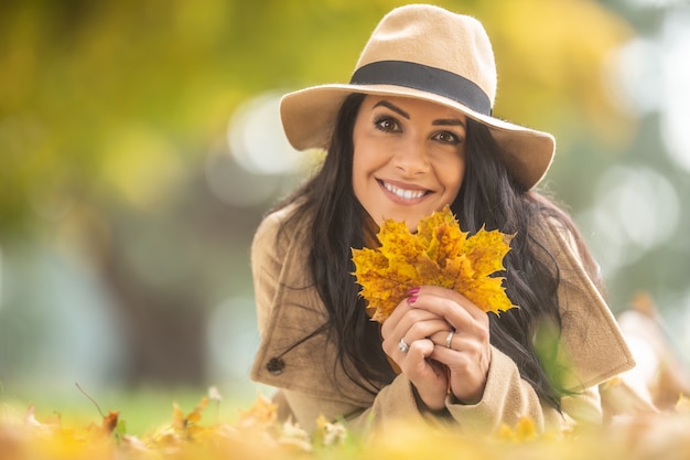Hermosa mujer en moda tiene hojas de otoño en el suelo.