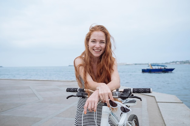Hermosa mujer montando en bicicleta Estilo de vida y salud en la ciudad Alegre joven pelirroja disfruta caminando por la ciudad