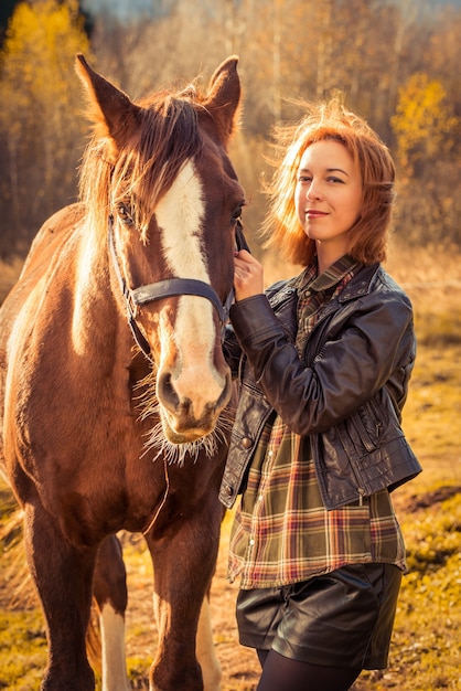 Hermosa mujer morena y caballo afuera en la naturaleza otoñal