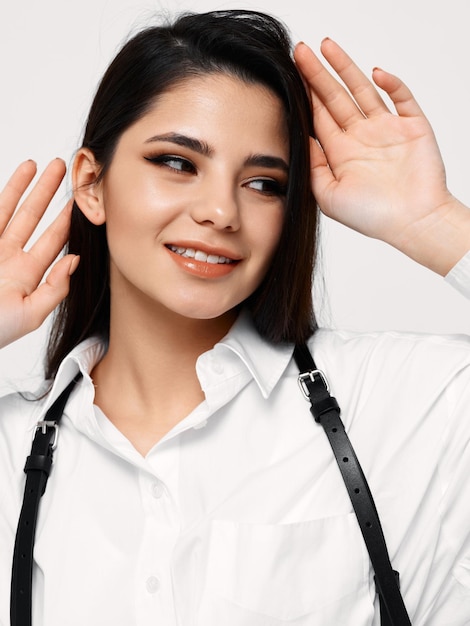 Hermosa mujer morena en camisa con tirantes toca su cabeza con las manos