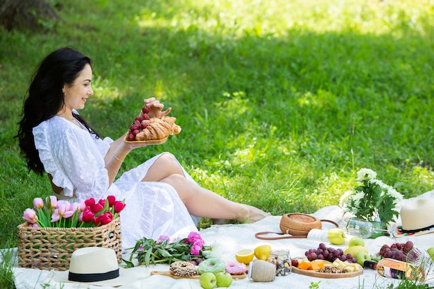 Hermosa mujer morena descansando en el parque sentado en una manta para picnic Relajarse en la naturaleza