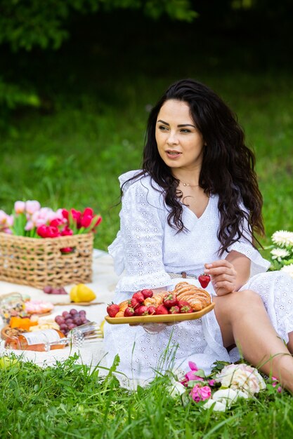 Hermosa mujer morena descansando en el parque sentado en una manta para picnic Relajarse en la naturaleza