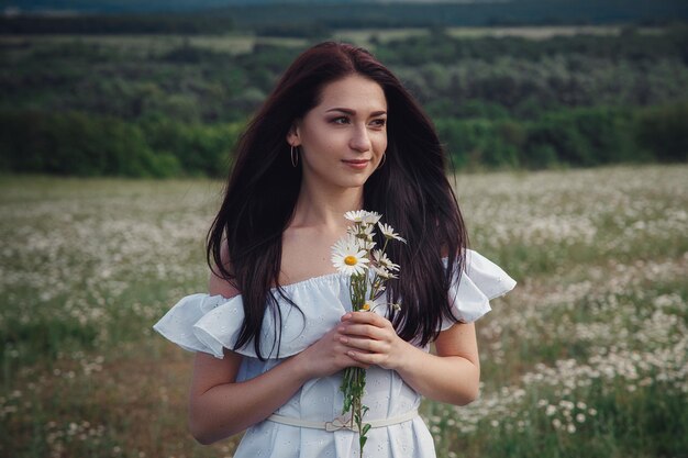 Hermosa mujer morena disfruta de la primavera en un campo de margaritas