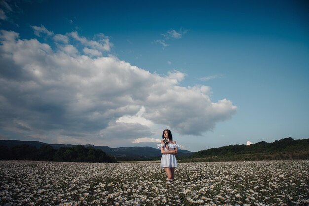 Hermosa mujer morena disfruta de la primavera en un campo de margaritas