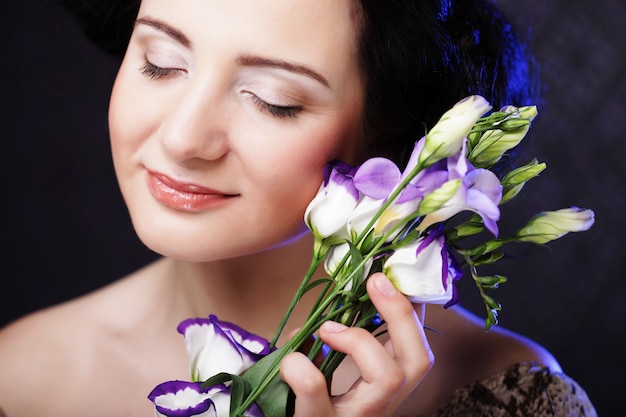 Hermosa mujer morena con flores lilas