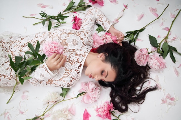 Hermosa mujer morena con flores de peonía