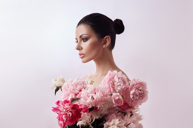 Hermosa mujer morena con flores de peonía