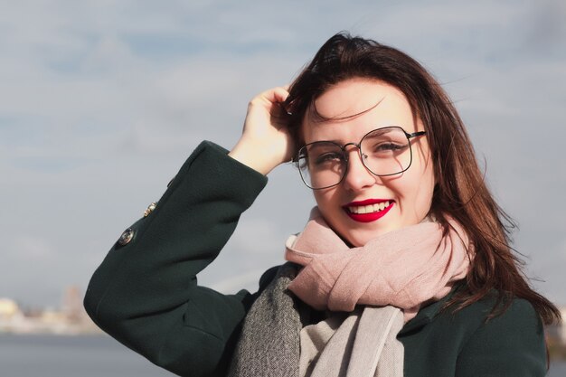 Hermosa mujer morena con gafas posando en la calle en el fondo de la ciudad. Primer retrato