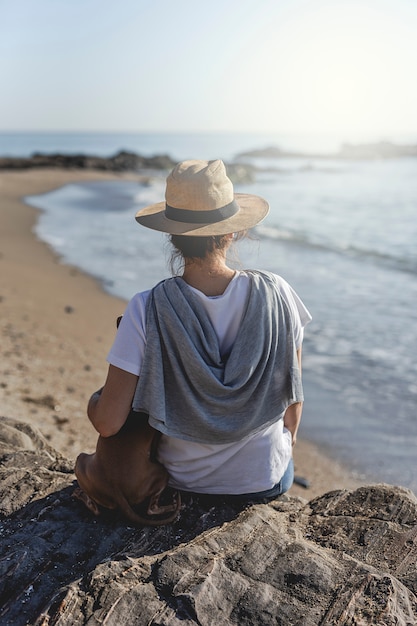 Hermosa mujer morena jugando con perro en la playa