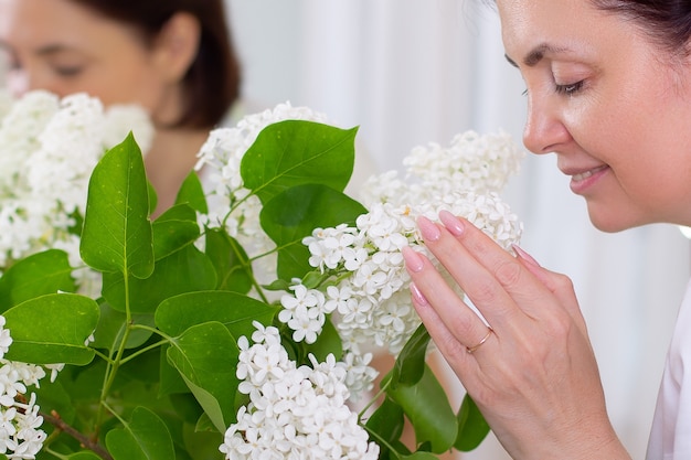 Hermosa mujer morena de mediana edad que huele a flor lila