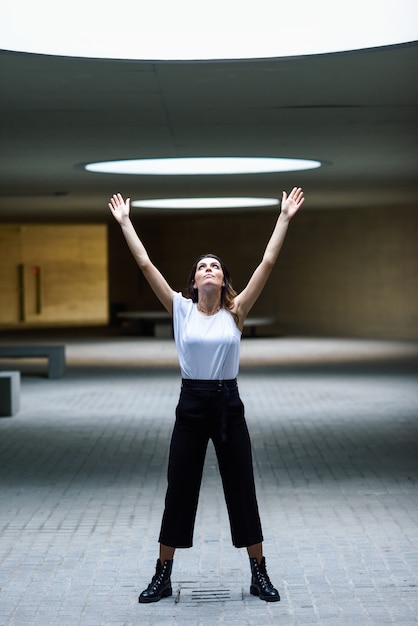 Foto hermosa mujer morena, modelo de moda, posando en edificio moderno.