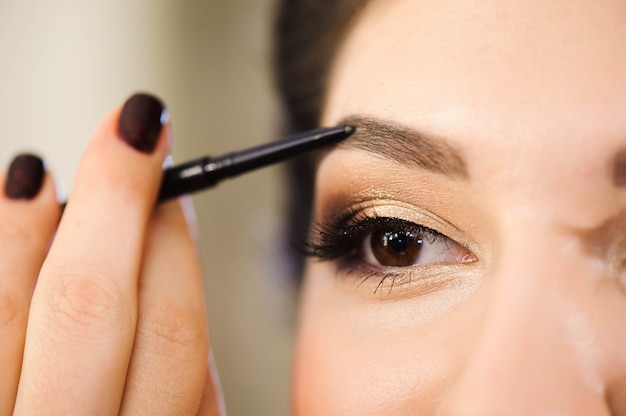 Hermosa mujer morena pinta las cejas. Rostro de mujer hermosa. Detalle de maquillaje. Chica de belleza con una piel perfecta.