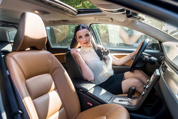 Hermosa mujer morena posando dentro del coche con llave