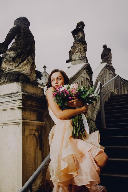 Hermosa mujer morena con un ramo de flores en un vestido rosa