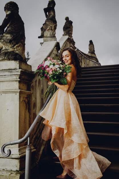 Hermosa mujer morena con un ramo de flores en un vestido rosa