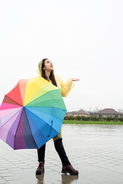 Hermosa mujer morena sosteniendo coloridos paraguas bajo la lluvia