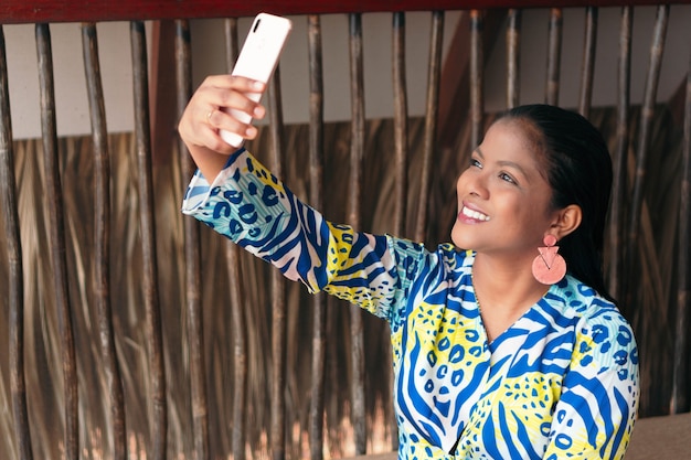 Hermosa mujer morena tomando un selfie con su teléfono en casa